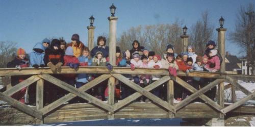 group of kids and adults on a snowy bridge